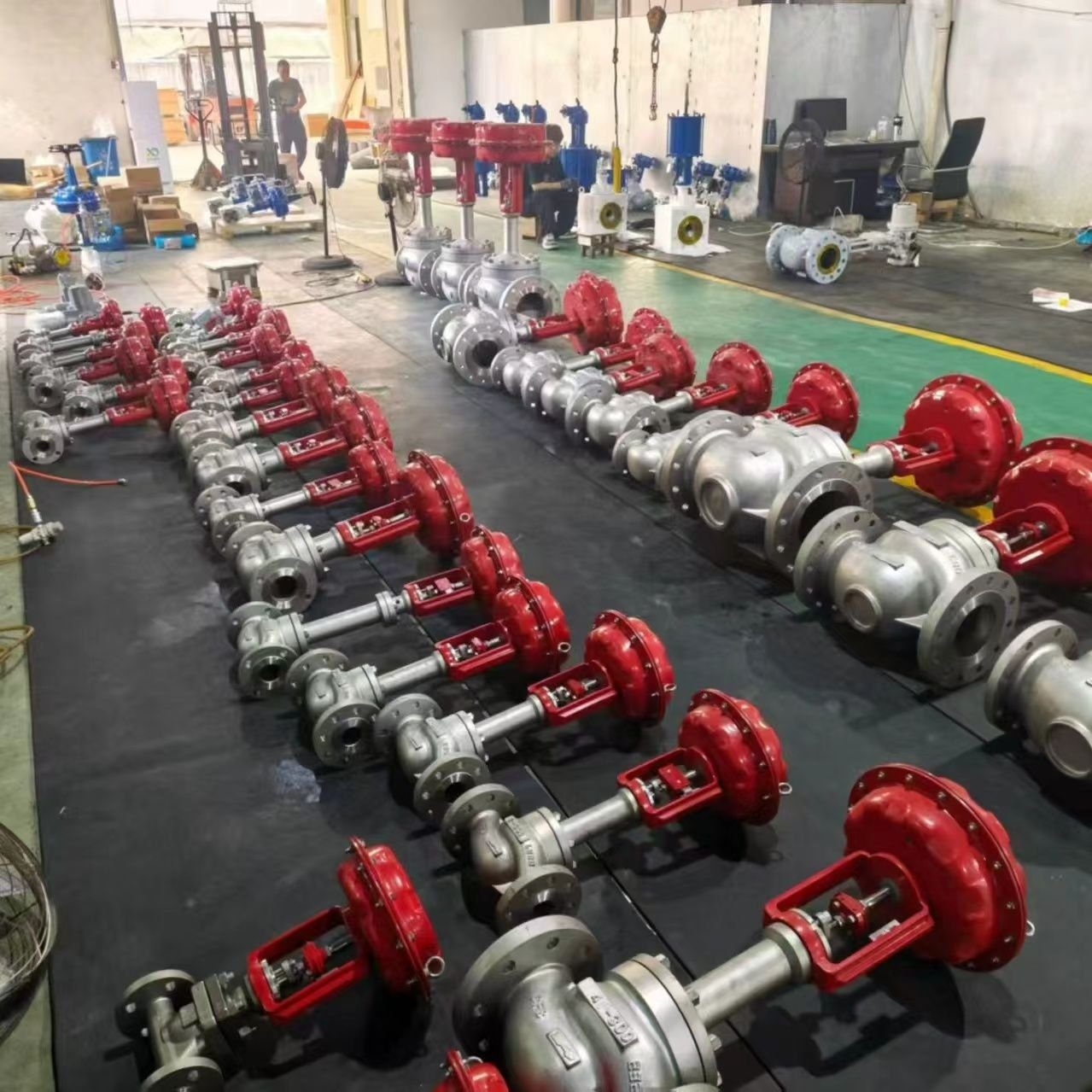 Multiple rows of pneumatic control valves with red actuators in factory